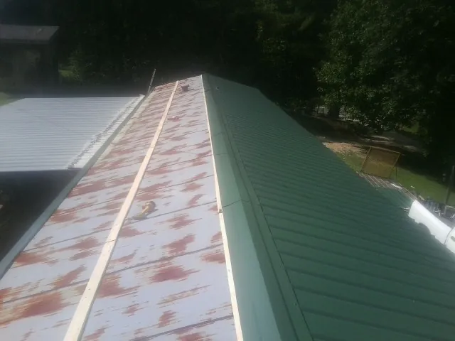 Old rusted panels beside newly installed green metal roofing — Wind Damage Roof Repair by Roofing Brothers in Seagoville