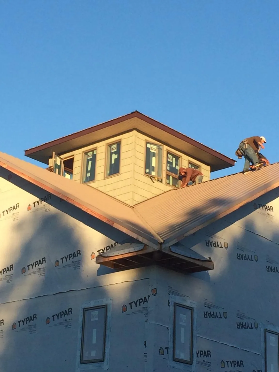 Roofers working around a rooftop cupola on a new metal roof at sunset — Roof Waterproofing in Seagoville by Roofing Brothers